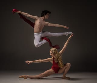 Two ballet dancers, one male and one female, in mid-leap, demonstrating a ballet pose.