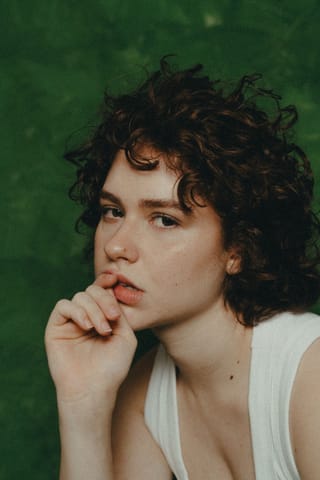 A young woman with curly hair in a thoughtful pose