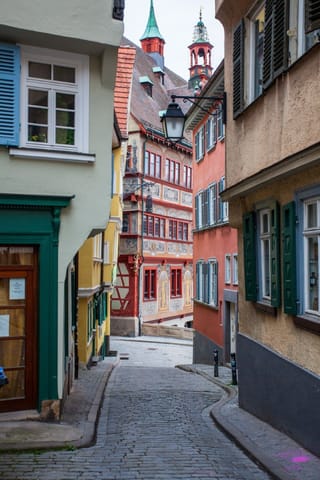 A serene and inviting alleyway in a quaint European town, featuring historic buildings and a charming street lamp.