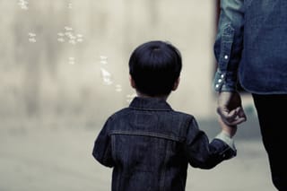 Child holding adults hand outdoors