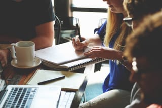 Coworkers in meeting with laptop and notes