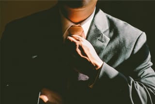 Man in dark suit adjusting tie