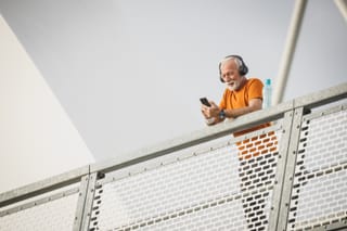 Older man using phone on balcony
