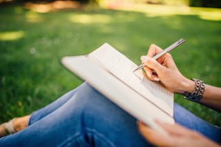 Person writing in notebook outdoors