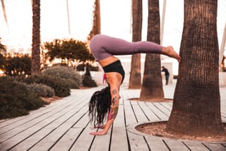 Woman performing an arm-balance yoga pose on a wooden boardwalk