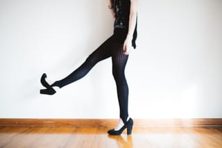 Woman wearing black tights and high heels against a bright background