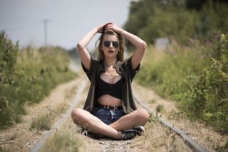 Woman sitting cross-legged in meditation on railroad tracks