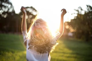 Woman running through field at golden hour