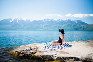 Woman sitting by mountain lake