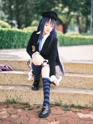 Woman sitting on steps adjusting striped knee high socks