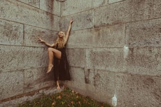Woman stretching beside a concrete wall outdoors