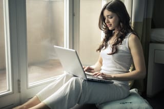 Woman using laptop by window