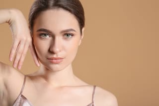 Woman posing for a studio beauty portrait against a beige background