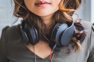 Close-up portrait of a woman with over-ear headphones around her neck