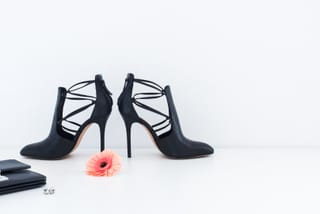 Pair of black strappy high-heel shoes is arranged on a clean white surface