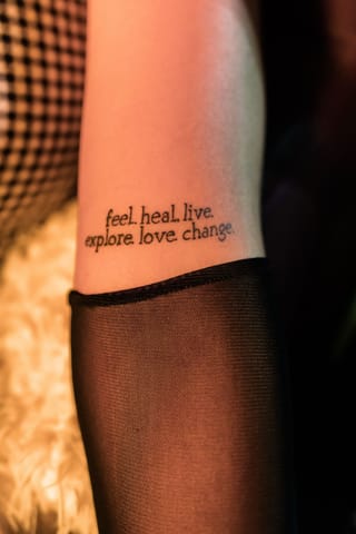 Close-up shows a small ankle tattoo above sheer black tights