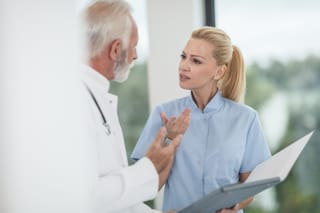 Doctor speaks with an older male patient while reviewing medical information