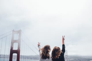 Two friends look toward the Golden Gate Bridge through light coastal fog