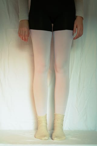 Front view shows legs in opaque white tights with light socks