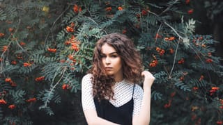 Woman poses among dense greenery and clusters of small red berries