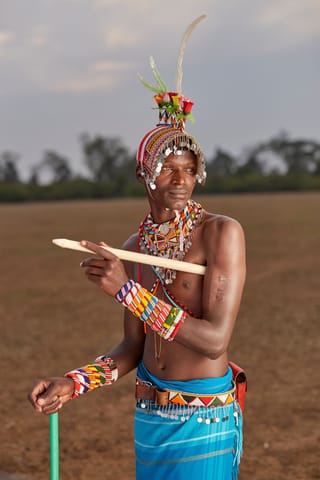 Man dancing outdoors in traditional beaded jewelry and clothing.