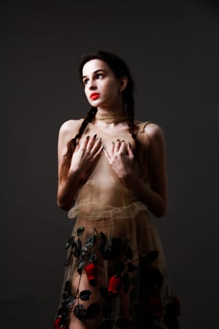 Woman in theatrical fashion posing in a dark studio.