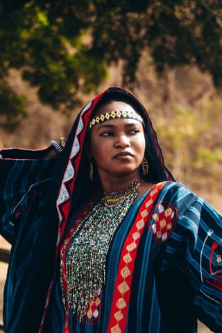 Woman in traditional dress and jewelry outdoors.