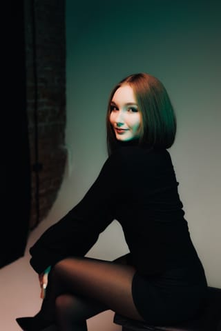 Woman wearing a black turtleneck dress in a studio.