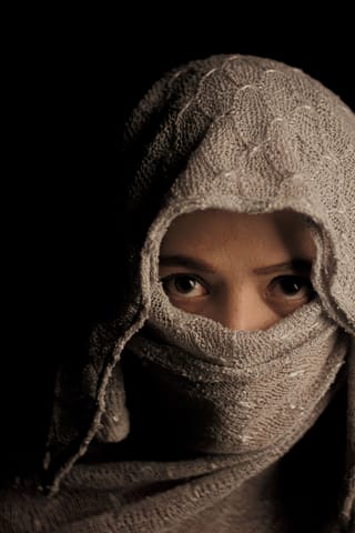 Woman with her face partially covered by a textured veil.