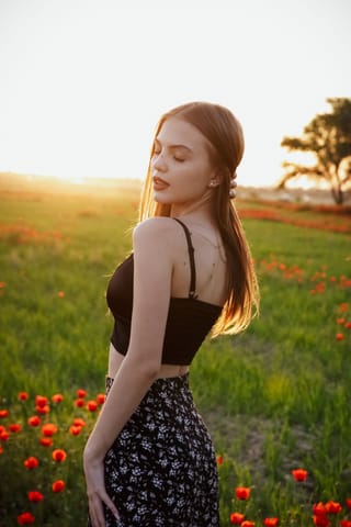 Woman standing in a field of red poppies and wildflowers.