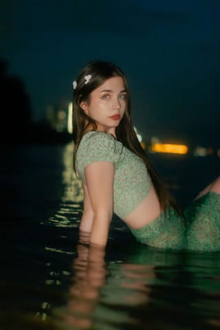 Woman standing in a swimming pool at night.