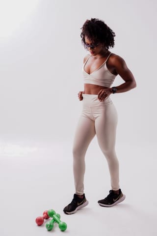 Woman in sportswear exercising with dumbbells in a studio.