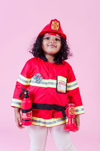 Child wearing a red firefighter costume in a studio portrait.