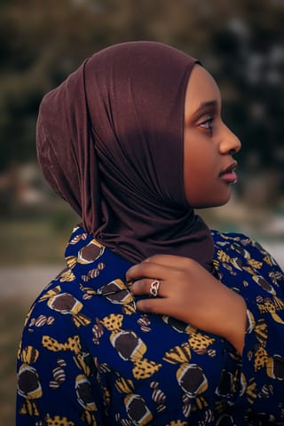 Woman wearing a brown headscarf in an outdoor portrait.