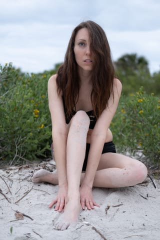 Woman sitting on a sandy beach in summer.