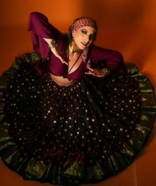 Woman posing in a bohemian dress with a flowing patterned skirt.