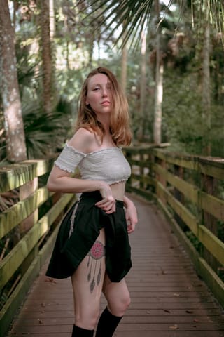 Woman standing on a wooden boardwalk in a forest.