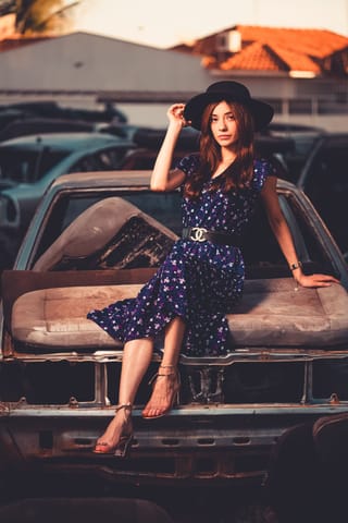 Woman in a polka dot dress posing on a vintage car.