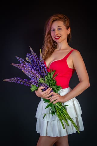 Woman wearing a red dress and holding a flower bouquet.