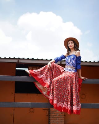 Woman wearing a colorful folk-style dress outdoors.