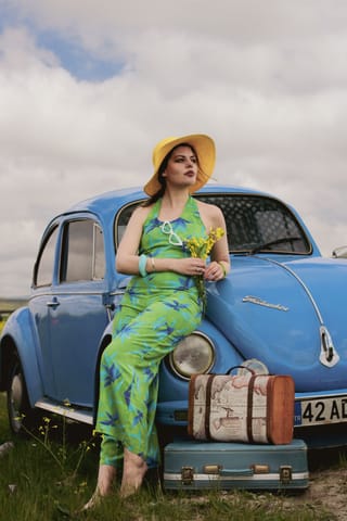 Woman green floral dress blue vintage car luggage