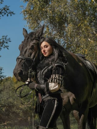 Woman posing with a black horse outdoors.