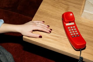 Red retro telephone on a wooden table.