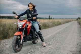 Woman riding a motorcycle on a country road.