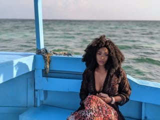 Woman sitting on a blue boat by the ocean.