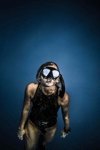 Female freediver wearing a mask underwater.