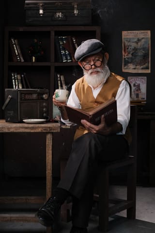 Senior man reading a book in a vintage library.