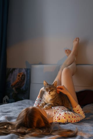 Woman relaxing in bed with cats.