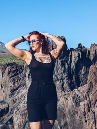 Woman hiking through rocky mountains in a black outfit.