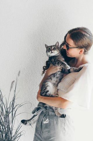 Woman hugging a tabby cat at home.